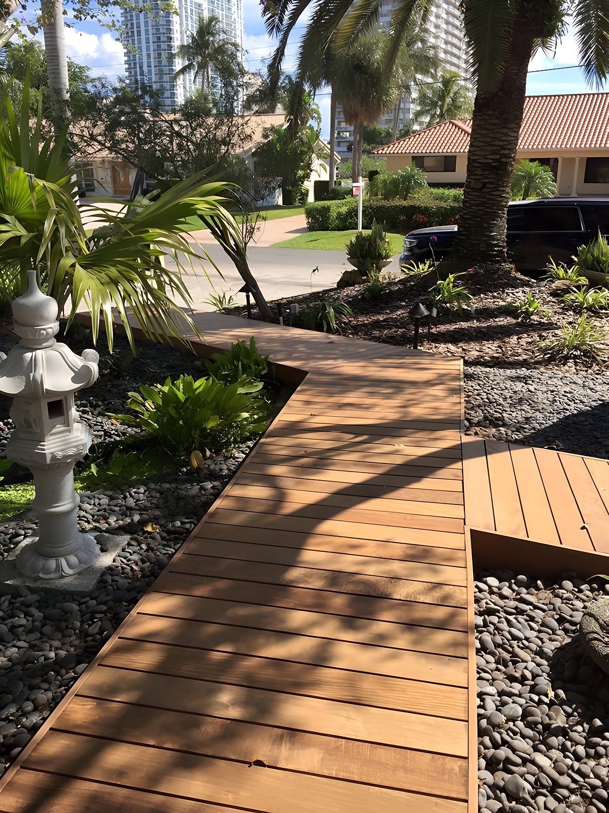 Luxury Ipe hardwood estate walkway winding through tropical garden with palm trees and river rock landscaping — South Florida by Contour Marine