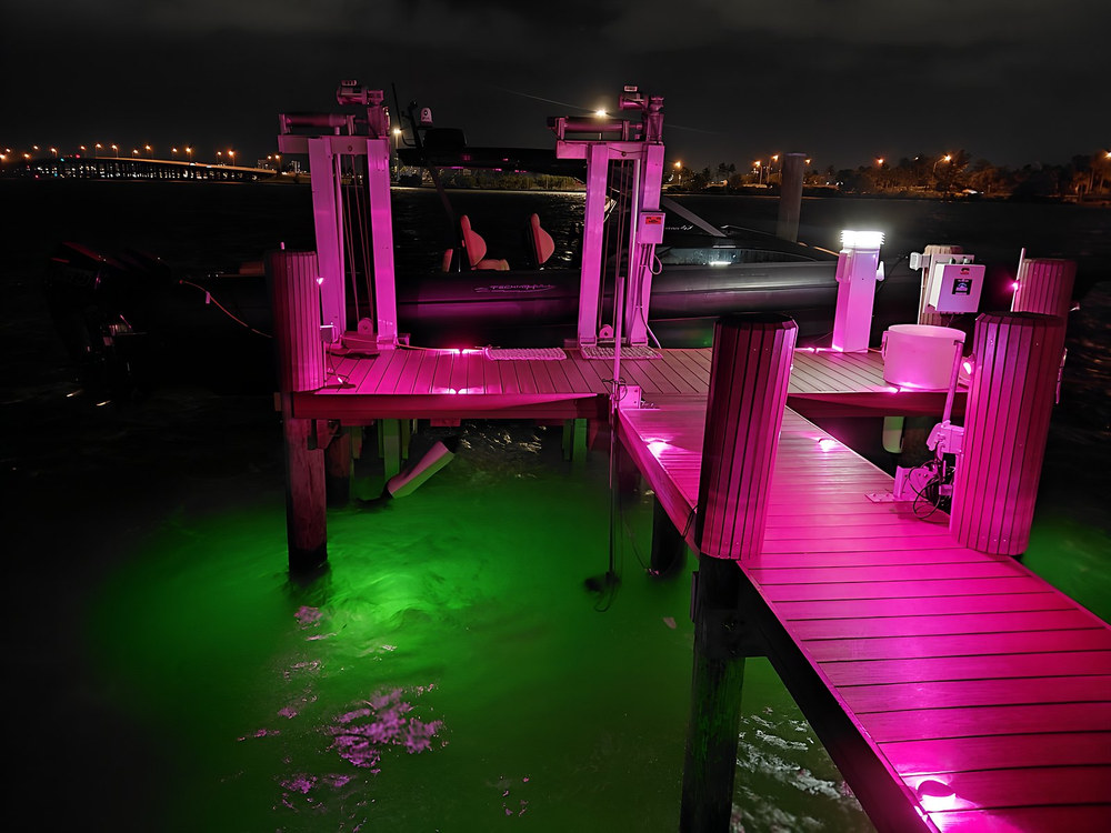Dock with vivid pink magenta LED lighting and green underwater glow — South Florida night