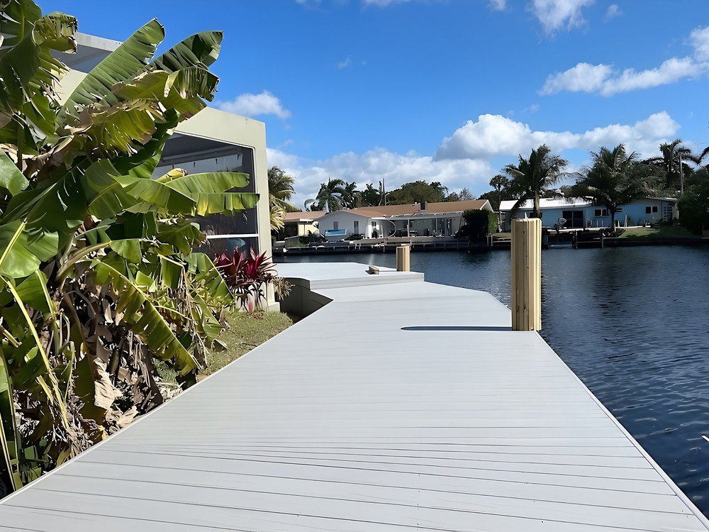 Grey composite dock curving along South Florida canal with tropical banana plants — Contour Marine