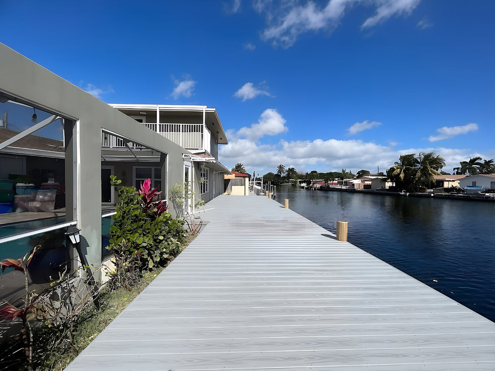 Long grey composite dock running alongside waterfront home on South Florida canal — Contour Marine