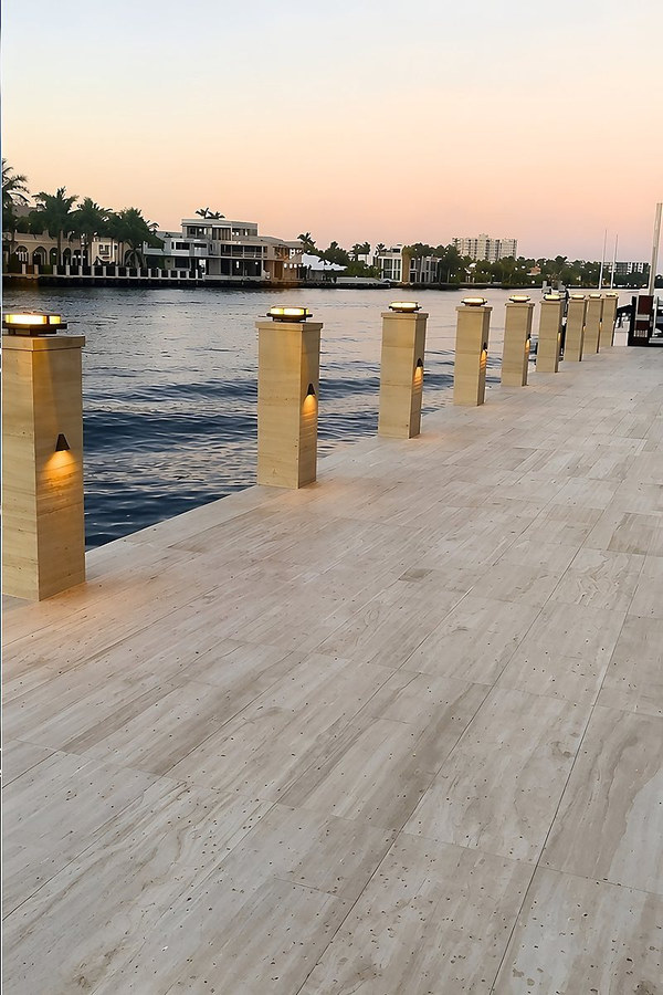Completed waterfront dock with travertine deck and illuminated bollards at sunset — South Florida
