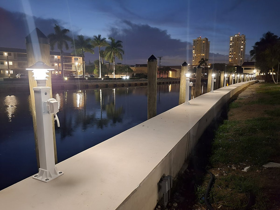 Completed seawall at night with illuminated dock lights reflecting on canal water — South Florida by Contour Marine